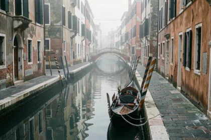 Canal vénitien désert en hiver avec gondole amarrée et brume matinale sur l'eau