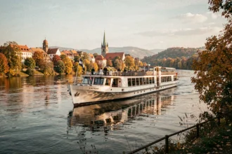 Bateau de croisière fluviale naviguant sur le Danube en automne avec des rives dorées et un village européen en arrière-plan